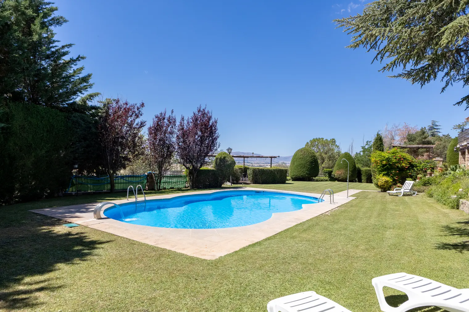 Piscina privada rodeada de césped y árboles
